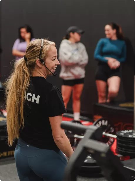 Une coach souriante avec micro-casque devant son groupe